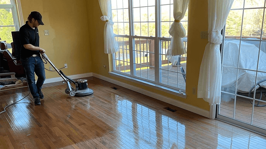 A ReCoat Revolution technician mechanically abrading an engineered hardwood floor before a fresh finish coat.