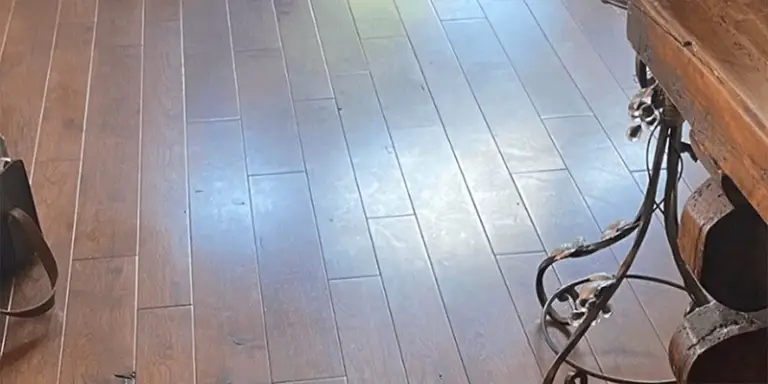 A residential hardwood floor that has been dulled and showing greasy footprints from Murphy's Oil Soap use, requiring a deep clean from ReCoat Revolution for restored shine.